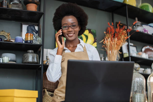 istock Afro saleswoman talking on mobile and typing on laptop 1313796716