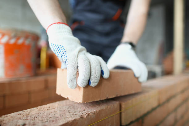 istock Man builder in protective gloves is building wall of bricks closeup 1313796809