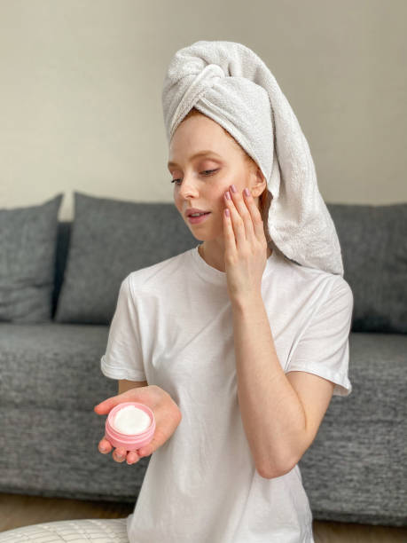 istock Young woman applying a moisturizer to her face at home 1313797237