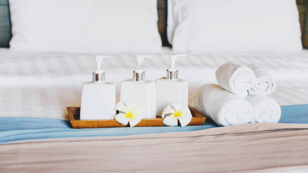istock bath accessories in white ceramic bottles ,blurred rolled towels and white blossom plumeria flower on hygiene comfortable bed in bedroom for spa ,recreation , hotel ,resort  ,welcome guest concept 1313797952