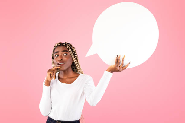 istock Pensive afro woman hoding speech bubble at pink studio 1313798071