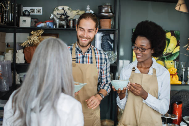 istock Two shop workers showing goods to female client 1313798106