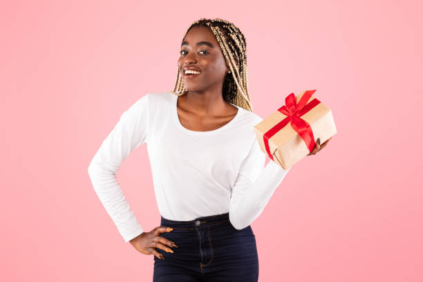 istock Happy black woman holding present box and smiling 1313798821