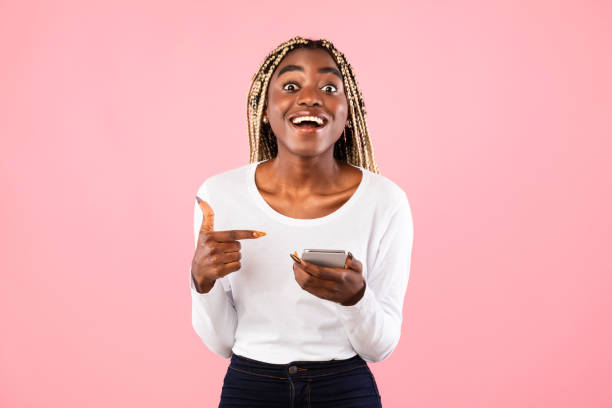 istock Excited black lady pointing at mobile phone at studio 1313799099
