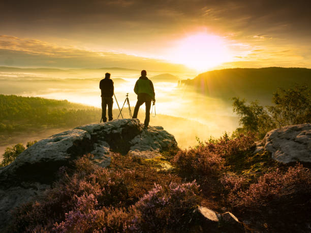 山の写真を撮る2人の風景写真家が鳴った。美しい自然の景色の中の重い霧 - walking night men sunset ストックフォトと画像