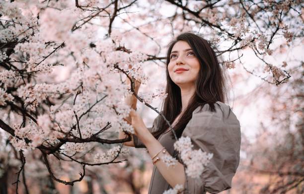 istock Beautiful Young Woman Standing By Cherry Blossom Tree 1313799937