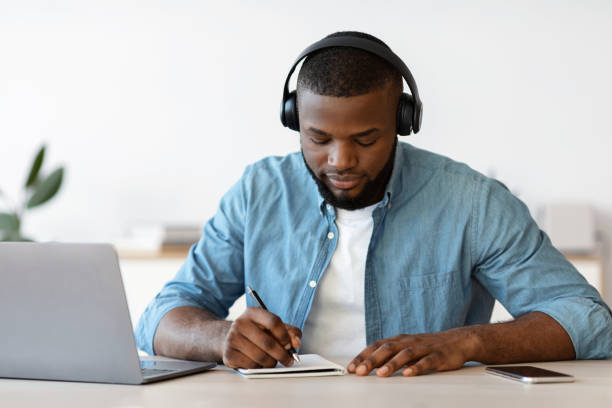istock Distance Learning. Young Black Guy In Headphones Study With Laptop At Home 1313800071