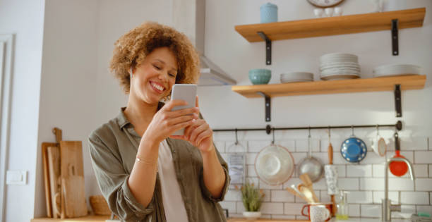 istock Young woman using smart phone in kitchen 1313800710