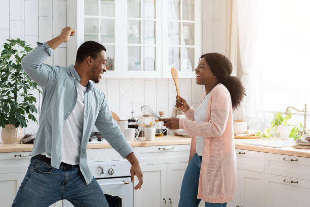 istock Domestic Fun. Black spouses playfully fighting in kitchen, using spatulas as weapons 1313800875