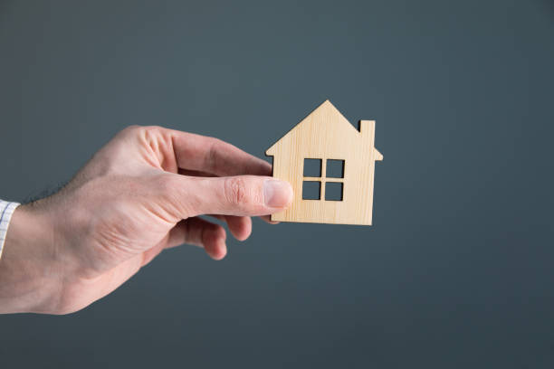 istock man hand holding wooden house 1313801120