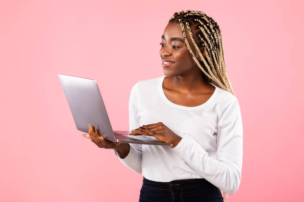 istock Smiling young black lady holding and using laptop 1313801142