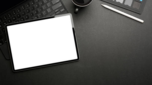 istock Top view of dark creative workspace with mock up tablet, accessories, mug and copy space 1313801171