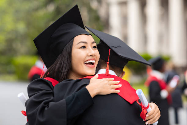 istock Cheerful asian lady hugging her boyfriend while graduation ceremony 1313801304