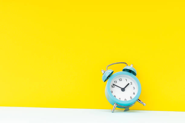 istock blue alarm clock over yellow background. studio shot. time concept. template for design 1313801889