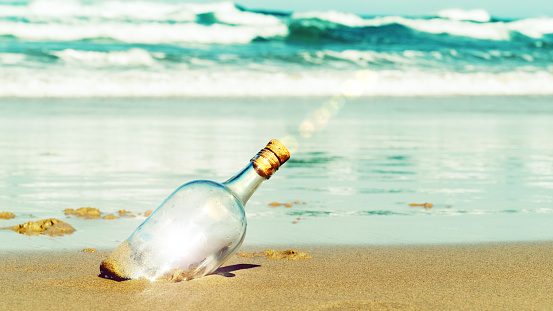A washed up bottle on the beach with a cork