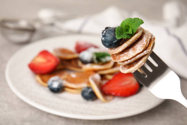 istock Fork with cereal pancakes, blueberry and mint on blurred background, closeup. Space for text 1313805221