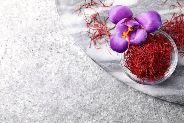 istock Dried saffron in bowl and crocus flowers on grey table, flat lay. Space for text 1313805780
