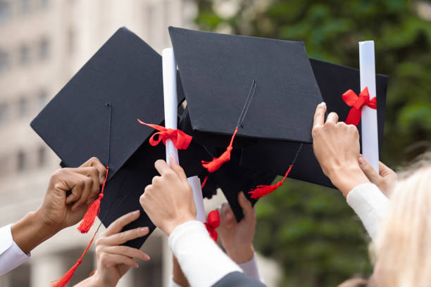istock Graduation hats and diplomas in students hands, closeup 1313806115