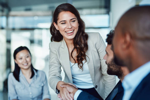 strzał młodej bizneswoman drżenie rąk z kolegą podczas spotkania w nowoczesnym biurze - recruitment zdjęcia i obrazy z banku zdjęć