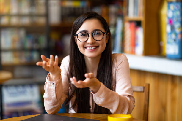 istock Remote tutoring concept. Young teacher talking and gesturing at camera, sitting in modern cafe, working distantly 1313808107