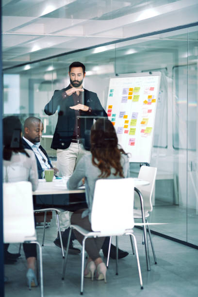 foto de un empresario entregando una presentación a sus compañeros de trabajo en la sala de juntas de una oficina moderna - worklife balance fotografías e imágenes de stock