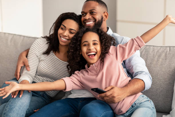 istock Happy young family watching television sitting on sofa 1313809185