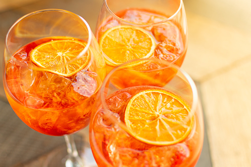 Italian aperitif aperol stpritz with ice and a slice of orange in large round glasses on a wooden table in a bar in Italy