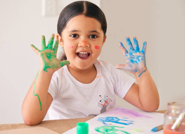 Shot of an adorable little girl sitting at home with water-based paint smeared on her hands This is so much fun! paper based equipment stock pictures, royalty-free photos & images
