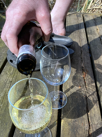 Man pouring white wine into two glasses.
