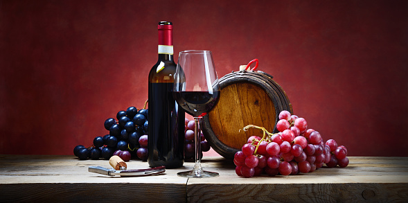 Red wine and grapes on wooden table in autumn vintage atmosphere.