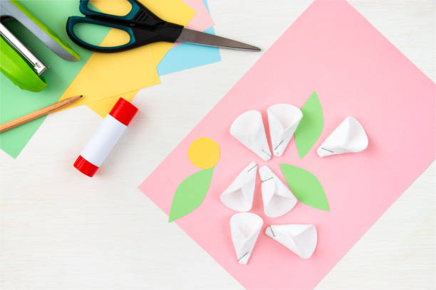 istock Cotton padded petals. Colored paper, stapler, scissors, scissors, pencil on a white table. Children's crafts for mother's day. Step-by-step instruction. Step 5. 1313817639