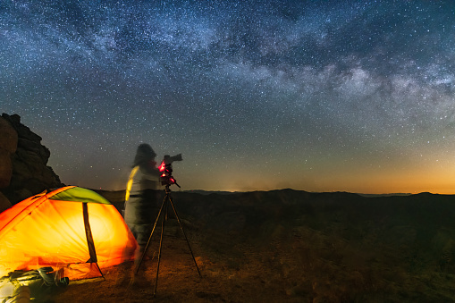 A star photographer is photographing a mountain tent camp under the Milky way