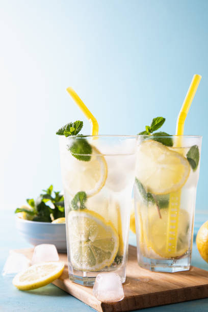 istock Two glass with lemonade or mojito cocktail with lemon and mint, cold refreshing drink or beverage with ice on blue background. Copy space 1313820219