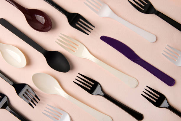 plastic disposable forks, spoons and knives on pink background