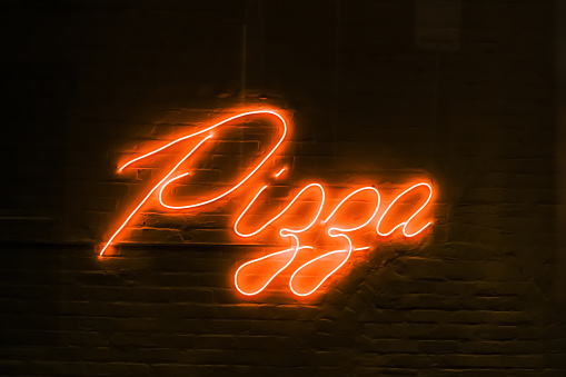 Pizza - neon sign on a brick wall at night. Restaurant takeaway pizzeria