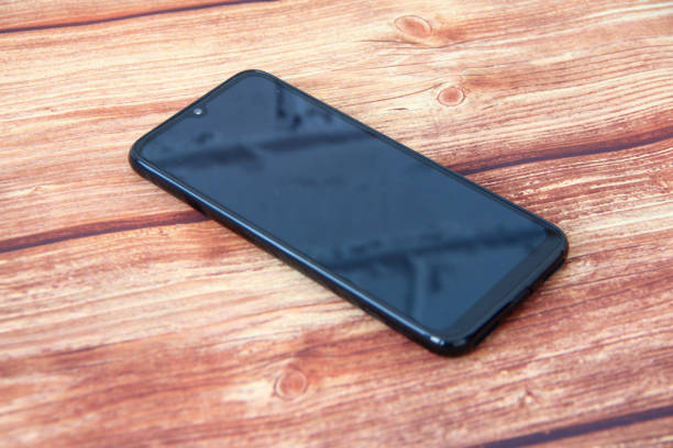 istock Smartphone with a black screen in which a brick wall is reflected on the wooden background 1313835351