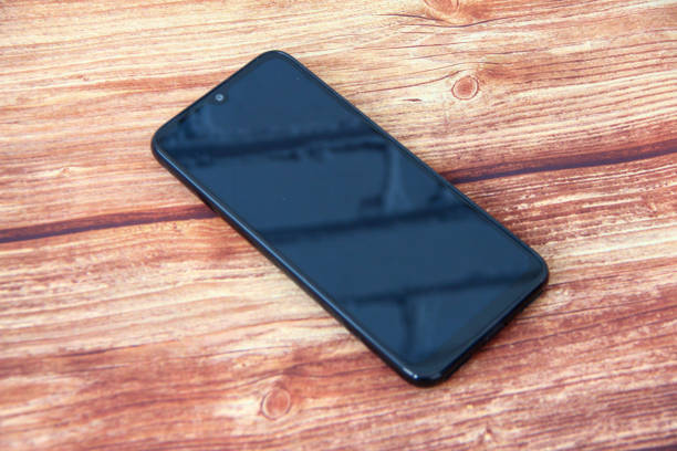 istock Smartphone with a black screen in which a brick wall is reflected on the wooden background 1313835353