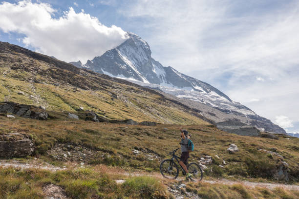 istock Man mountain biker rides on trail below the Matterhorn mountain 1313836520