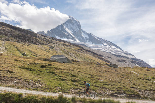 istock Man mountain biker rides on trail below the Matterhorn mountain 1313838206