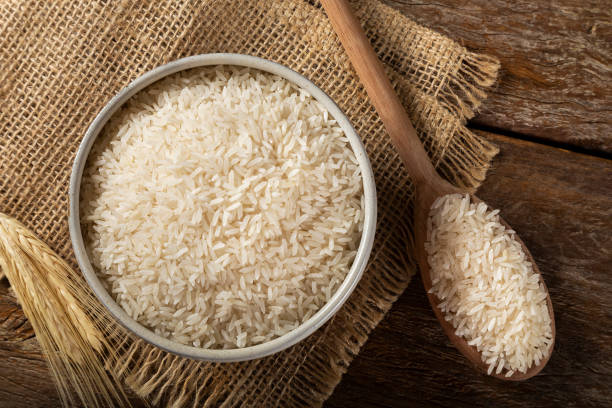 istock Raw white rice in a ceramic bowl on brown wooden background. 1313838270