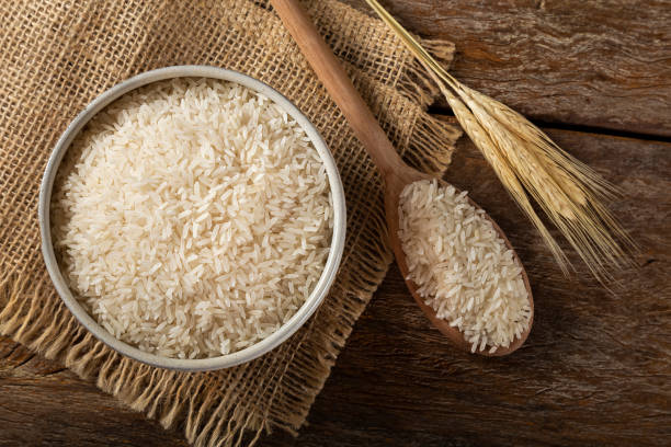 istock Raw white rice in a ceramic bowl on brown wooden background. 1313838274