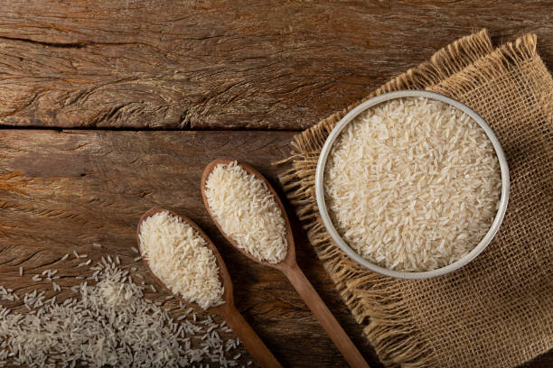 istock Raw white rice in a ceramic bowl on brown wooden background. 1313838290