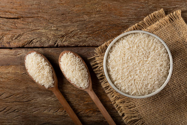istock Raw white rice in a ceramic bowl on brown wooden background. 1313838299