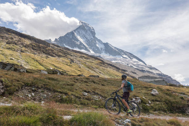 istock Man mountain biker rides on trail below the Matterhorn mountain 1313838318