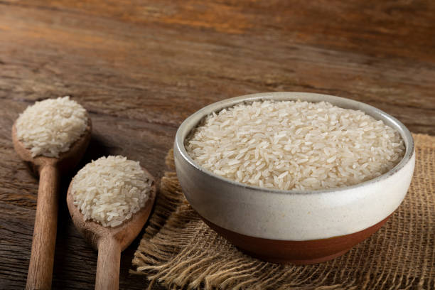 istock Raw white rice in a ceramic bowl on brown wooden background. 1313838328