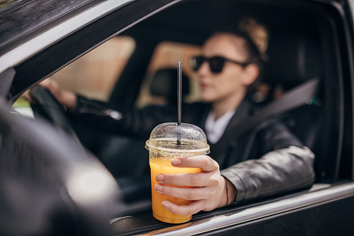 Young woman drinking juice  and driving car