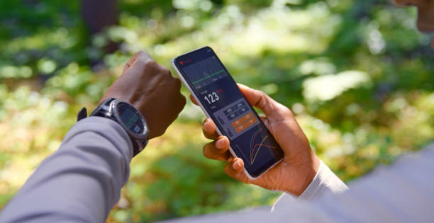 mujer usando software de seguimiento en teléfono inteligente y reloj inteligente - ordenador para utilizar como accesorio fotografías e imágenes de stock