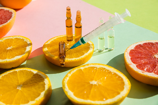 ampoules and Serum with Vitamin C. Organic cosmetics concept. Lemon, lime, orange, tangerine and ampoules on a light background