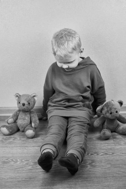 istock A three-year-old caucasian boy sits alone on the floor next to teddy bears. 1313844462