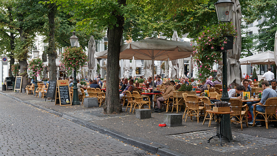 Maastricht, Limburg, Netherlands, september 22nd 2016, large group of people sitting (eating, drinking, talking, reading) at a sidewalk cafe on the \